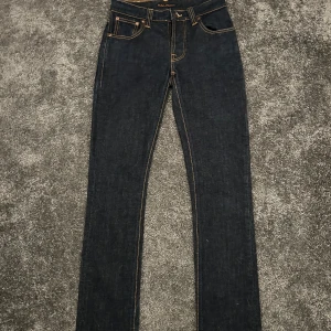 Mörkblå jeans från Nudie Jeans - Ett par galet snygga nudie jeans i populära modell grim tim. Bra skick på byxorna jeansen är råa/raw vilken betyder att dom kommer bli fadear så dom blir som jeansen på sista bilden. Midja 36cm: längd 102cm: innerben 72cm