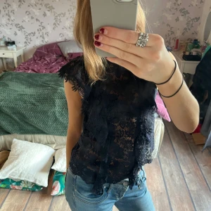 Mörkblå spetsblus - Säljer en elegant mörkblå spetsblus med korta ärmar. Blusen har ett vackert mönster och är perfekt för en stilren look. Passar bra till både jeans och kjol.