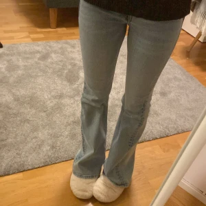 Blå bootcut jeans - Snygga blå bootcut jeans med klassisk femficksdesign. De har en bekväm passform och är perfekta för en avslappnad stil. Jeansen har en dragkedja och knapp framtill.