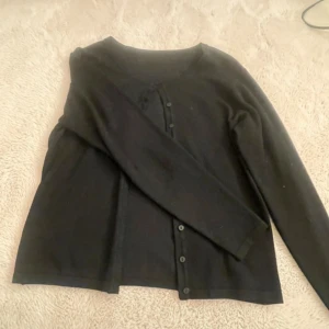 Svart kofta - Säljer en stilren svart kofta från hm med knappar framtill. Koftan är helt ny i storlek S 