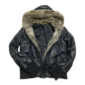 Svart pufferjacka med fuskpäls🖤 - Snygg svart pufferjacka med fuskpäls på huvan. Jackan har dragkedja framtill och ribbade muddar vid ärmslut och nederkant. Jätte snygg design. I väldigt bra skick förutom en dekoration knapp som saknas på ena sida (kolla sista bilden), men den syns knappt och förstör inte användningen. Storlek S och den stämmer! Skriv vid frågor❕