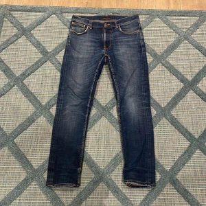 Blå jeans från Nudie Jeans🍾⚜️ - Snygga blå jeans från Nudie Jeans med en klassisk femficksdesign och orange sömmar. De har en slim passform och är tillverkade i slitstarkt denim. Perfekta för en stilren look. Bra skick!