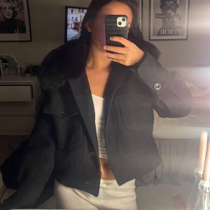 Svart pälsa jacka från Meotine - Snygg svart croppad jacka från Meotine med en pälsdetalj på kragen som även går att ta av om man skulle vilja de,Jackan har knappar framtill och två stora fickor på bröstet. Dock så har en åkt av men inget man tänker så mycket på💕