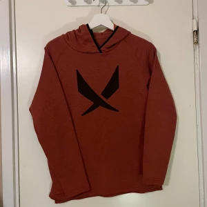 Hoodie från SOC - Säljer en snygg rostfärgad hoodie från SOC. Den har en cool svart logga på framsidan och är perfekt för höst och vinter. Tröjan är långärmad och har en bekväm passform. 