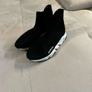 Svarta sneakers från Balenciaga - Säljer ett par svarta Balenciaga sneakers i mycket bra skick. Köpte till min man men dem är lite små i storeken De har en strumpliknande design med vit sula och Balenciaga-logga på sidan. Perfekta för en stilren och modern look. Kommer med originalkartong och dustbag. Använt 1-2 gånger , kan tyvärr inte lämna tillbaka eftersom dem är använda . 
