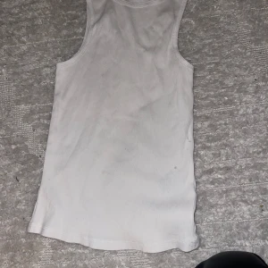 Vit ribbad linnetopp från Divided - Säljer en enkel och stilren vit ribbad linnetopp från Divided. Perfekt för sommardagar eller som ett basplagg i garderoben. Toppen är i storlek S och har en bekväm passform. Passar till både vardag och fest! 🌟