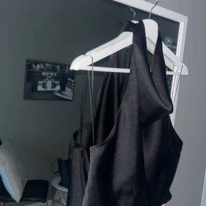 Svart satintop öppen rygg zara - Säljer denna svarta satintop med knappar i nacken och som är öppen i ryggen. Från Zara i storlek S. Kan ha små små trådar som sticker ut och ser ut som bandet vid där man knäpper blivit lite tunnare. Jättefin att ha på fest! 