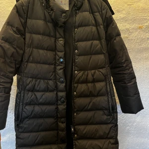 Moncler dunkappa  - Svart damkappa /dunkappa från Moncler. Den har några år på nacken men väldigt fin modell och inga skavanker/skador. Avtagbar luva. Strl 1(36)