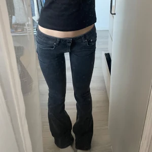 Svarta bootcut jeans - Säljer ett par snygga svarta/mörkgråa bootcut jeans i mycket bra skick. De är lågmidjade och har en tight passform upptill som övergår i en utsvängd stil vid anklarna. Perfekta för både vardag och fest! 🖤