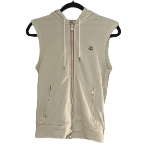 Moncler White Logo Hooded Tricot Vest - Säljer min Moncler väst i storlek Small då den har blivit för liten för mig. Västen är i mycket bra skick, inga defekter eller slitage. Hör gärna av dig om du har några frågor eller vill veta mer! Ny pris 6500kr. Äkta såklart!