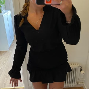 Svart klänning från Bik Bok - Säljer en superfin svart klänning från Bik Bok i storlek S. Den har en v-ringad hals och långa ärmar med volangdetaljer vid ärmslut och nederkant. Superfin passform😍 Perfekt för fest eller en utekväll!🖤 Julafton eller nyår kanske?🪩🎆🎄🤶