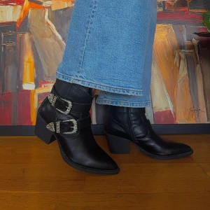 Svarta boots med spännen - Säljer ett par snygga svarta boots med coola silverfärgade spännen. De har en bekväm klack och spetsig tå, vilket ger dem en stilren look. Perfekta för höst och vinter, och funkar både till vardags och fest. Dragkedja på sidan för enkel på-av. 