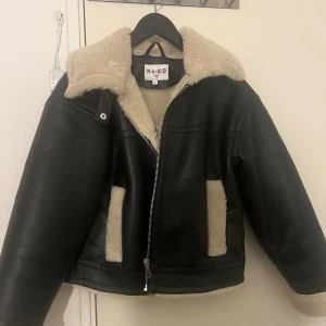 Jacka - Svart jacka med fuskpälsfoder. Jackan har en dragkedja framtill och två fickor på sidorna. Jackan är i bra skick.