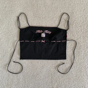 Bershka Hello Kitty svart topp med öppen rygg - Otroligt snygg topp från Bershka med broderad Hello Kitty design, rosettband och öppen rygg. Aldrig använd, helt ny. Den skickades utan prislapp. Utan anmärkningar. 