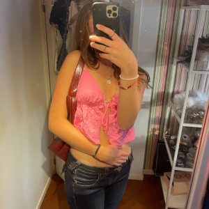 Söt rosa topp - Tröjan är ganska kort men ser mycket kortare ut eftersom jag har långmidjade jeans på bilden. Toppen är i bra skick och har knappt använts. Den knyts där fram. Banden går att justera.