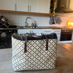 Malene Birger väska - Säljer min Totebag från malene Birger väska i den ”normala”(mellan) storleken. I fint skick trots axelremsbanden då de tyvärr blir slitna på alla efter ett tag. Skulle säga att färgen är cremevit/gul ish med svart mönster, banden är mörkbruna. 🩷🩷