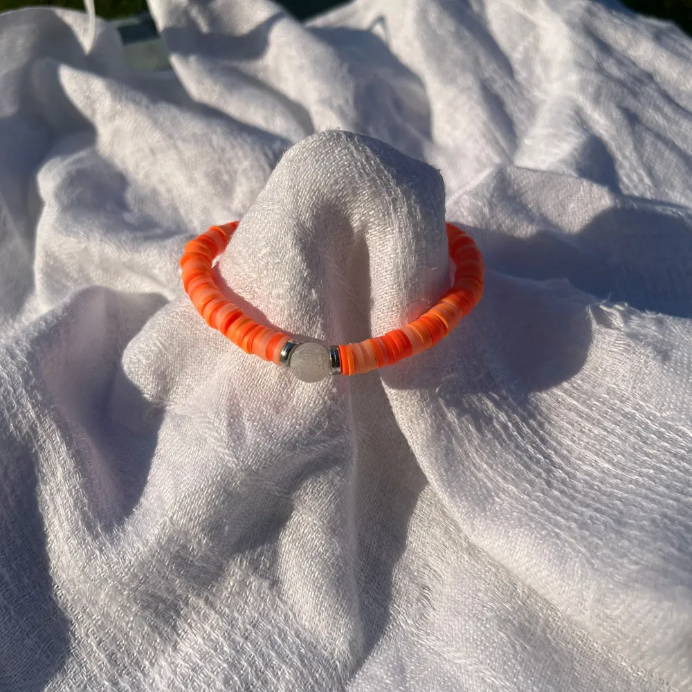 Säljer ett snyggt orange armband med små, platta pärlor. Armbandet har en enkel och stilren design med en silverfärgad detalj i mitten. Perfekt för att liva upp vilken outfit som helst! Passar bra till sommarens alla äventyr. 🌞. Accessoarer.