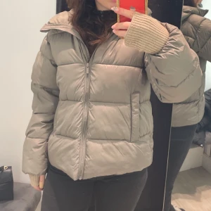 Beige pufferjacka - Säljer en supermysig beige pufferjacka i mycket bra skick. Den har en dragkedja framtill och långa ärmar. Perfekt för höst och vinter när du vill hålla dig varm och snygg. Jackan har en normal passform och är riktigt skön att ha på sig. Perfekt för både vardag och chill dagar ute. Nypris 800kr