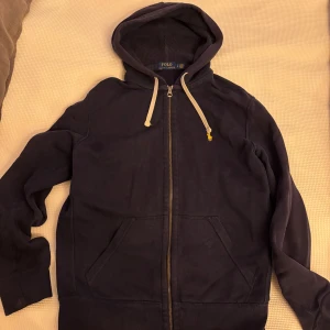 Ralph Lauren Full-Zip Hoodie navy - Säljer en snygg mörkblå hoodie från Polo. Den har en dragkedja framtill och en klassisk huva med snören. . Den är i bra skick och inga fel.