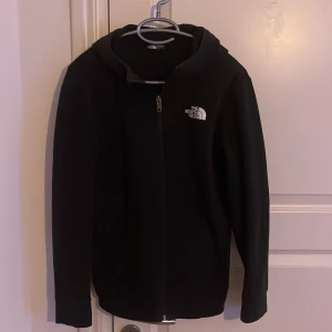 Svart fleecejacka från The North Face - Säljer denna snygga zip hoodie från The North Face, den är i bra skick skulle säga 8/10, passar dig som är runt 170, kom pm om någon fråga