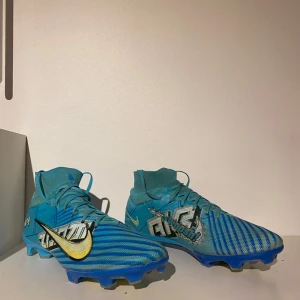 Blå Nike mercurial superfly fotbollsskor FG - Säljer ett par blå Nike fotbollsskor i bra skick. Skorna har en cool randig design med gula detaljer och snörning. Perfekta för fotbollsträning eller match. De har en tight passform och är gjorda för att ge bra grepp på planen. FG