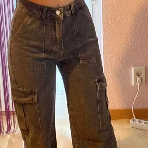 Svarta cargopants - Säljer ett par svarta cargopants i mycket bra skick. De är högmidjade och har en loose passform med praktiska fickor på sidorna. Perfekta för en avslappnad och trendig look. Passar till både vardag och fest!