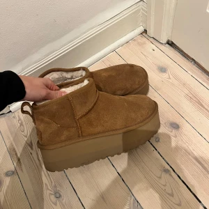 Mini Platform UGGS - Säljer ett par snygga bruna UGG mini platsform boots i mocka med pälsfodring. De har en  platåsula som ger extra höjd och komfort. De är endast använda 3 gånger så som nya. Köpt på Wakakuu för 2100kr förra hösten. OBS. Storlek 38 på lappen men de är stora och passar mig som har 39 i alla andra skor