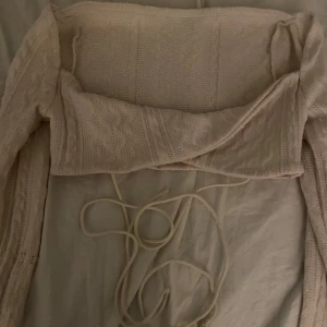 Beige stickad bolerotopp från Shein - Säljer en superfin beige stickad bolerotopp från Shein. Den har långa ärmar och ett snyggt knytband framtill. Perfekt för höst och vår när du vill ha något lätt men ändå stiligt. Passar perfekt över en klänning eller topp för en extra touch.