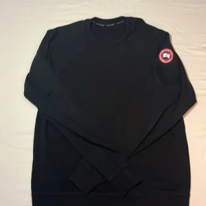 Svart tröja från Canada Goose - Säljer en svart tröja från Canada Goose i storlek M. Den är i mycket bra skick och har en snygg broderad logga på ärmen. Perfekt för höst och vinter, och den är tillverkad i Italien. Passar både till vardags och lite finare tillfällen. Köpt i Köpenhamn för 2425 DKK =3 760 SEK. Hör av er vid intresse och funderingar ⚡️⚡️