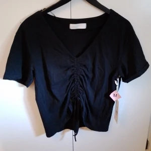 Oanvänd Topp Med Snörning - Oanvänd svart topp med Snörning från Sasma i storlek m. Köpt för 80 kr men säljer för 50.  Katt finns i hemmet