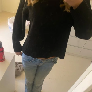 Svart stickad tröja - Säljer en mysig svart stickad tröja i bra skick. Den har en normal passform och långa ärmar, perfekt för höst och vinter. Ribbad kant vid ärmslut och nederkant ger en snygg detalj. Passar både till jeans och kjol för en avslappnad look.