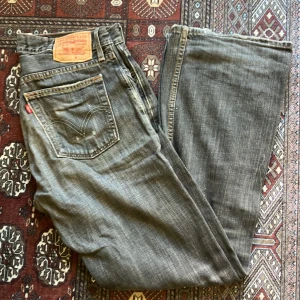 Levi's 527 Low Boot Cut Jeans - Säljer ett par klassiska Levi's 527 jeans i grått. De har en low boot cut stil och är tillverkade i 100% bomull. Perfekta för en avslappnad look med en snygg passform. Använda men i bra skick. Passar både till vardags och fest!