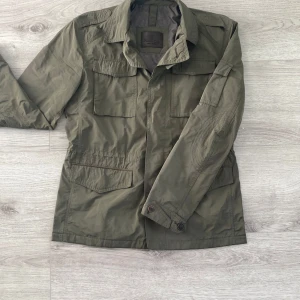Olivgrön fieldjacket - Säljer denna mycket detalj-rika fieldjackan från Massimo Dutti. Flera knappar, fickor och vikelser ger jackan möjlighet att ta flera olika skepnader. För mer specifika bilder/beskrivningar eller övriga frågor, kontakta gärna!