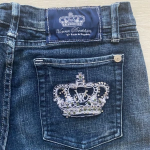 Jeans från Victoria Beckham för Rock & Republic - Snygga jeans i mörkblå denim med broderade kronor på bakfickorna. 2000s still. Jeansen har en klassisk passform och är i mycket bra skick. Dem är lite korta 