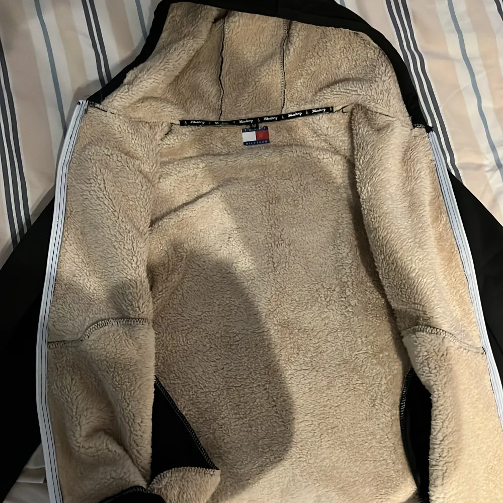 Säljer en svart jacka från Hilfiger i storlek M. Den har ett mysigt teddyfoder som håller dig varm under kalla dagar. Jackan har dragkedja och två praktiska fickor framtill. Perfekt för höst och vinter!. Jackor.