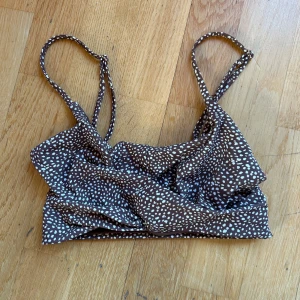 Brun prickig bikiniöverdel - Säljer en superfin brun bikiniöverdel med vita prickar. Den har smala axelband och en bekväm passform. Endast använd 1 gång & sen tvättat 🤎