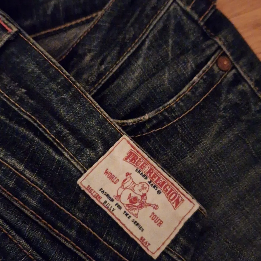 Säljer ett par snygga True Religion jeans i mörkblå denim. De är lågmidjade och är bootcut. Jeansen har coola detaljer på bakfickorna och är i bra skick. Perfekta för både vardag och fest 💕 *strl W27*. Jeans & Byxor.