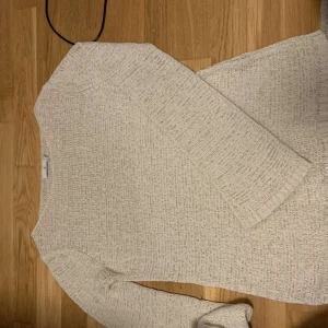 Beige stickad tröja - Mysig beige stickad tröja i bra skick. Perfekt för höst och vinter med sin varma och bekväma design. Tröjan har långa ärmar och en enkel, stilren look som passar till det mesta. Ett måste i garderoben för kyliga dagar!