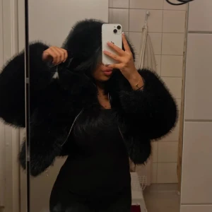 Svart pälsjacka med huva - Säljer en supermysig svart pälsjacka med huva. Perfekt för kalla dagar när du vill känna dig både varm och elegant. Jackan har en dragkedja framtill och är i mycket bra skick. Den är oversized och passar perfekt för höst och vinter. Perfekt för en utekväll eller bara när du vill känna dig extra fin.🖤 (fuskpäls)