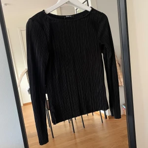 Svart ribbad långärmad topp från Gina Tricot - Säljer en stilren svart ribbad topp från Gina Tricot. Den är långärmad och perfekt för både vardag och fest. Tyget är super fint och nästan lite glittrigt vilket gör den super fin som utekvälls topp! Tycker verkligen om den men tyvärr har den blivit lite för liten.