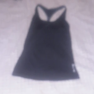 Svart linnetopp från SOC - Säljer en svart linnetopp från SOC i storlek 140. Perfekt för träning med TCS Airflow-teknologi som håller dig torr och bekväm. Toppen har en sportig design med brottarrygg och är tillverkad i ett lätt och andningsbart material.