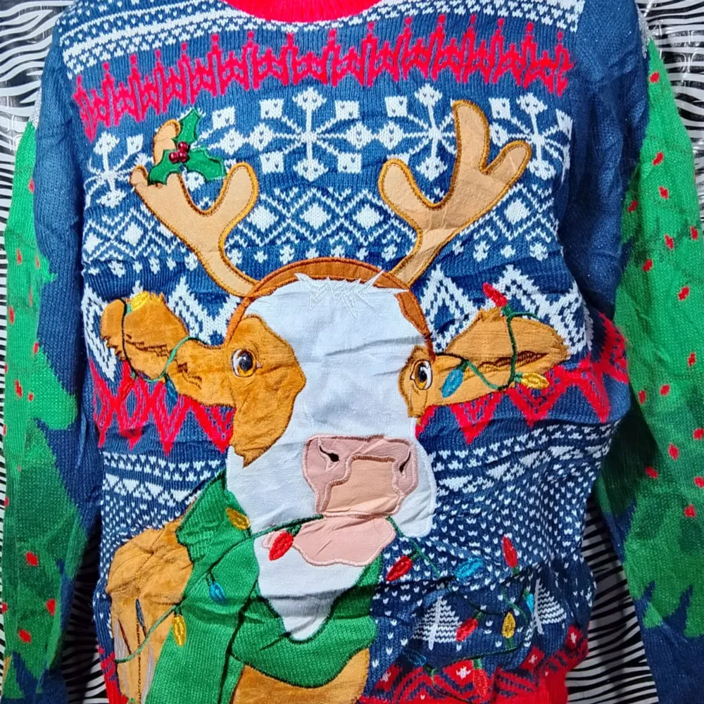 Säljer en supermysig blå jultröja med ett stort renmotiv på framsidan. Tröjan har ett klassiskt vintermönster i vitt och rött, och gröna ärmar med röda detaljer. Perfekt för julfesten eller en mysig dag hemma. Den är långärmad och har en skön passform. 🎄. Neuletakit & Villapaidat.