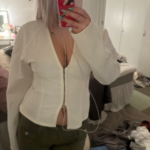 Vit långärmad tröja med knappar - Säljer en snygg vit långärmad tröja med knappar framtill. Perfekt för både vardag och fest! Tröjan har en figurnära passform och är superbekväm. Passar perfekt till jeans eller kjol. Hör av dig vid intresse! 🤍