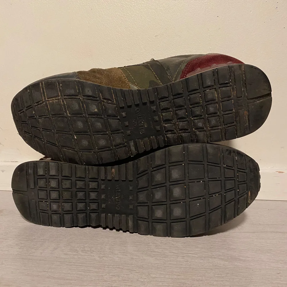 Säljer ett par snygga Valentino Garavani sneakers i grönt och brunt. De har en cool design med en mix av skinn och mocka, samt en unik logga på hälen. Skorna har snörning och en bekväm sula för vardagsbruk. Perfekta för dig som vill ha stil och komfort i ett! Finns skav i hälarna men endast i tyg.  Är även intresserad av byte. . Skor.