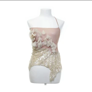 Elegant oneshoulder topp med paljetter - Säljer en superfin oneshoulder topp i rosa och beige med paljetter och blommiga detaljer. Perfekt för festliga tillfällen! Toppen har en asymmetrisk design och en unik kombination av material som ger en lyxig känsla.