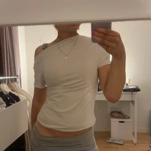 cremefärgad oneshoulder topp - Säljer nu min stilrena vita oneshoulder topp. Den har en tight passform och passar perfekt till allt!! tyvärr ingen lapp så vet inte storleken men den sitter bra på mig som har xs/s i storlek!!