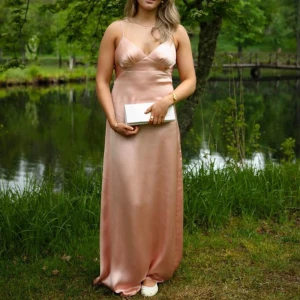 Balklänning  - Säljer min jättefin ljusrosa långklänning i satin med smala axelband och v-ringad urringning som jag hade på balen. Hade även en sjal över axlarna eftersom det duggade under min bal. Den har exakt samma färg och det ser otroligt lyxigt ut ihop! Båda är endast använda en gång! Jag är 173 cm lång!! Från pretty lavish! Tror inte den säljs längre. Den är storlek 40 men jag har 38 och den passar mig perfekt😌Öppen för förhandling!