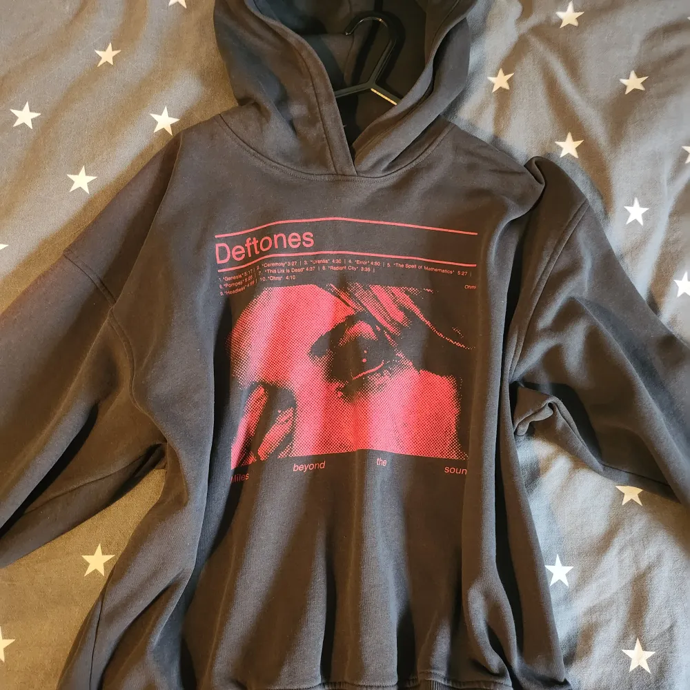 Säljer en svart hoodie med tryck av Deftones i rött. Den har en cool design med ett ansikte och låttitlar på framsidan. Perfekt för höst och vinter, och den är i bra skick. Grym för alla Deftones-fans! 🖤 köpt här på plick Storlek s/m. Hoodies.