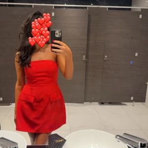 Röd axelbandslös klänning - Säljer en superfin röd axelbandslös klänning i kort modell. Perfekt för fest eller nyår! Klänningen har en enkel och elegant design som framhäver figuren. Den är i mycket bra skick och redo för nya äventyr. Passar perfekt för en kväll ute eller en speciell tillställning. 💃✨