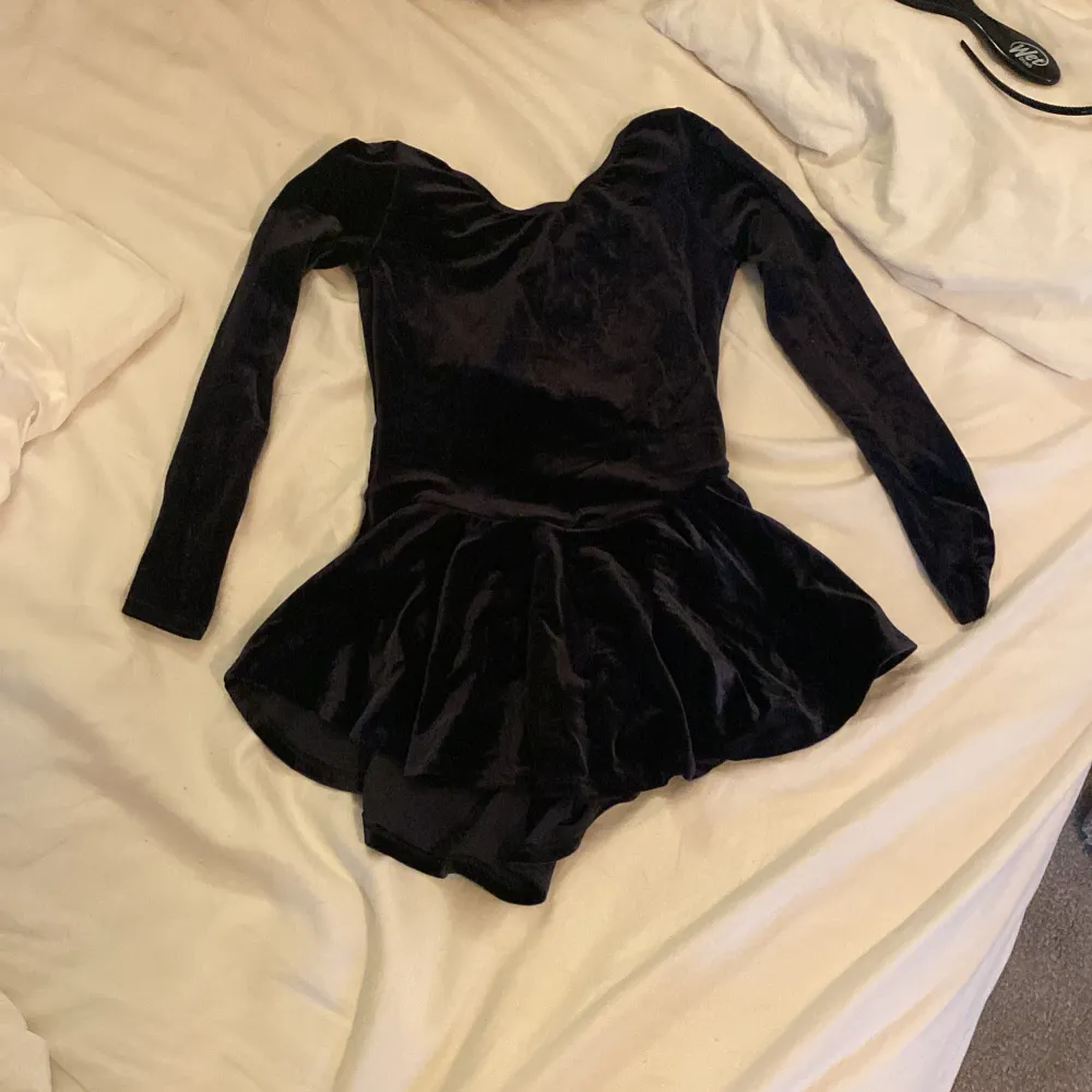 Säljer en elegant svart klänning i mjuk sammet. Den har en tight passform med långa ärmar och en kort kjol med volangdetalj. Perfekt för kånståknings träningar.Klänningen är i mycket bra skick och redo att bäras av någon som vill glänsa! Den sitter tajt och skönt på kroppen också ganska stretchig🤍🤍. Mekot.